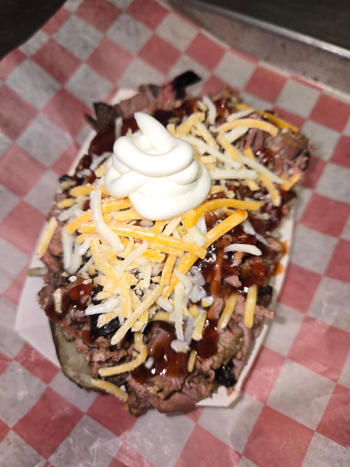 Loaded baked potato piled with chopped brisket, cheese, BBQ sauce and sour cream